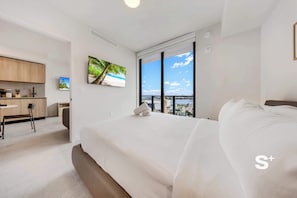 Ein modernes Hotelzimmer mit einem großen Bett, einem Schreibtisch und Blick auf den Strand durch ein großes Fenster.