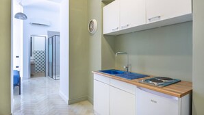 Een moderne keuken met witte kastjes, een blauwe spoelbak en een ingebouwd fornuis.