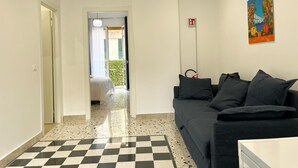 Eine Hotellobby mit einem Schachbrettmuster-Boden, einer dunklen Couch, einem Gemälde an der Wand und einem Feuerschutzausgangsschild.
