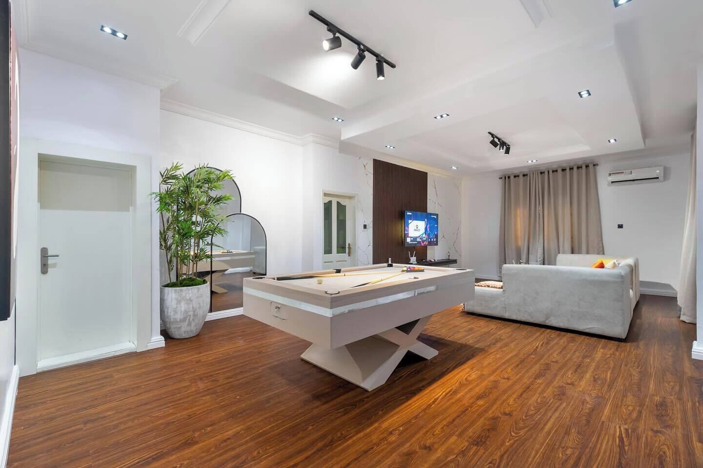A modern living room with a pool table, a sofa, and a TV.