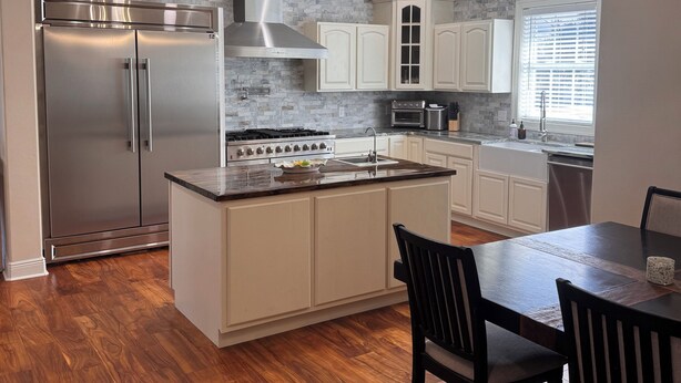 Una cocina moderna con un refrigerador de acero inoxidable, una estufa a gas y piso de madera.