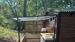A wooden deck with two lounge chairs, a small wooden structure with a sink, and a bamboo fence. - Chalet in the woods (Meyreuil)
