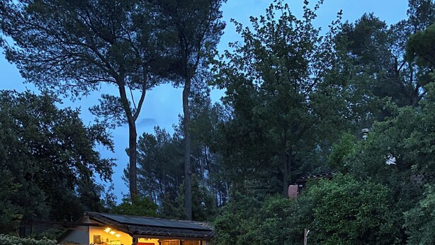 A swimming pool with a wooden deck and a small building with a red door. - Chalet in the woods (Meyreuil)