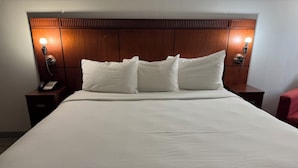 A hotel room with a large bed, two bedside tables, a telephone, and wall-mounted lamps. - Orange Studios (Orange)