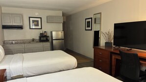 A hotel room with two beds, a kitchenette, a TV, and a mirror. - Orange Studios (Orange)