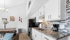 Una cucina moderna con mobili bianchi, piani in granito e forno integrato.