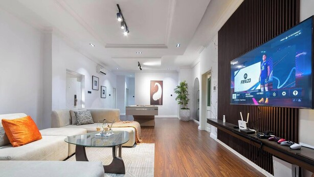 A modern living room with a large flat-screen TV, a sofa, a coffee table, and a pool table. - The Bless Navic Hotel (Aba)