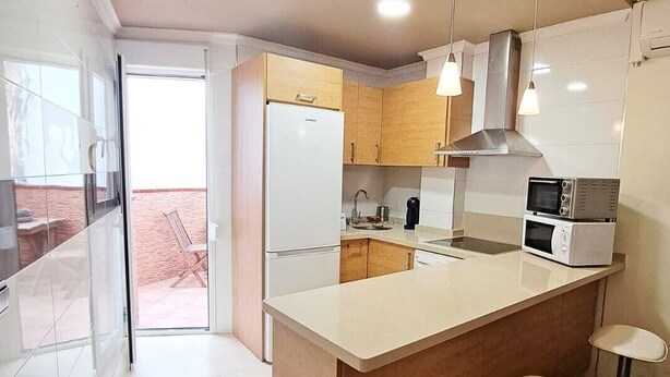 Una cocina moderna con una isla central, taburetes de barra de acero inoxidable y vistas a un patio exterior.