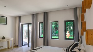 Een slaapkamer met een bed, een bureau en uitzicht op groen.