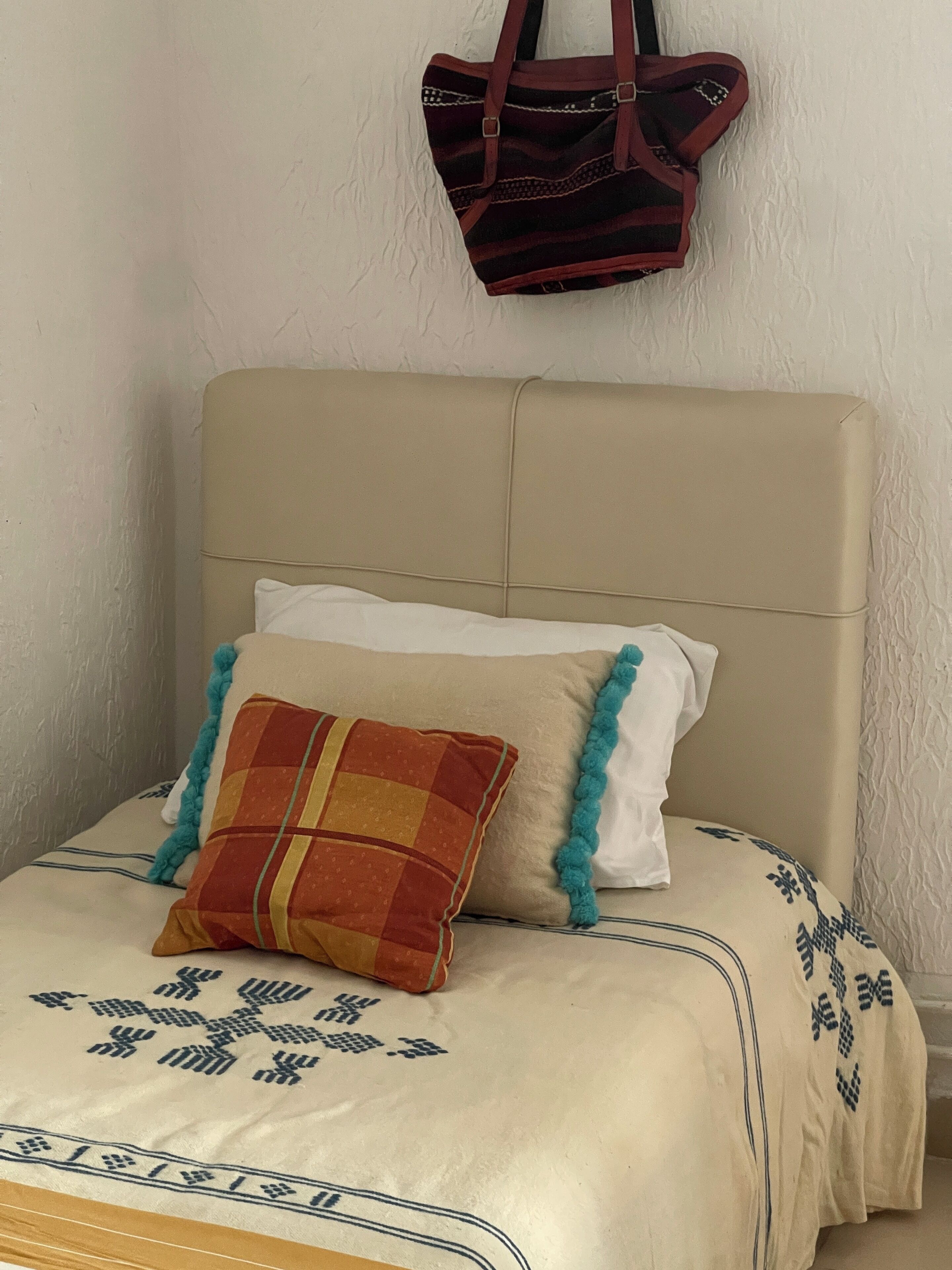 A bed with a beige headboard, a patterned bedspread, and two pillows.