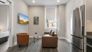 A modern living room with a sofa, armchair, and a large window. - Upscale 2BR Getaway in the Heart of NOLA (New Orleans)