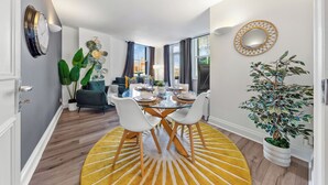 A modern dining area with a glass table, white chairs, and a yellow rug. - Prime Liverpool Street Retreat (London)
