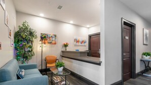 A reception area with a blue sofa, a small table with a magazine, a potted plant, and a Christmas tree with lights. - Stylish 2BR Suite in Historic NOLA (New Orleans)
