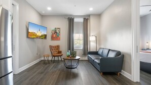Una sala de estar moderna con un sofá gris, una mesa de centro de madera y un televisor montado en la pared.