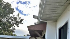 A residential building with a covered porch, a gravel pathway, and a small garden area with rocks and plants. - Serene Getaway in Dauis with Pool and Shared Kitchenette (Dauis)