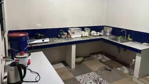 A compact kitchen with a white countertop, blue backsplash, and a sink. There are various kitchen appliances and utensils on the counter. - Serene Getaway in Dauis with Pool and Shared Kitchenette (Dauis)