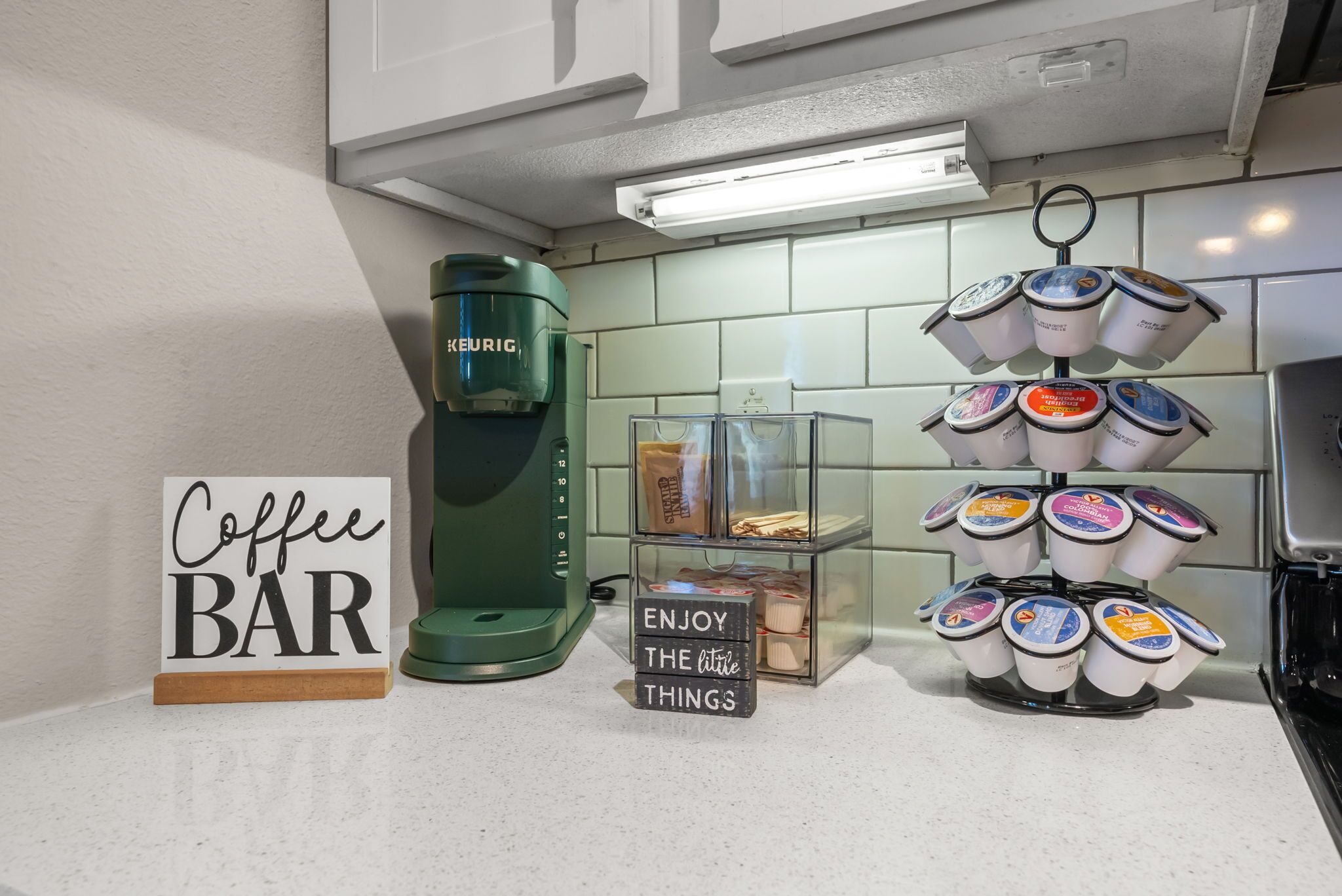 A coffee bar setup with a Keurig coffee maker, a sign that reads "Coffee BAR", and a display of coffee pods.
