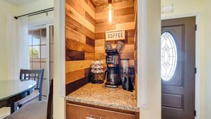 A kitchen with wooden walls, a coffee station, and a dining area with a table and chairs. - NEW, Spacious 2 BR,Short Walk to the Beach,Private (Myrtle Beach)