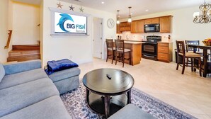 A modern living room with a grey sofa, a round coffee table, and a kitchen area featuring wooden cabinets and a microwave. - NEW, Spacious 2 BR,Short Walk to the Beach,Private (Myrtle Beach)