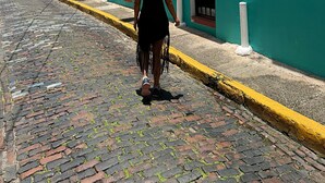 A cobblestone street with a teal building, a woman in a black dress and white hat walking away, and a 'PARE' sign visible. - San Juan Home DownTown Perfect for family and group (San Juan)