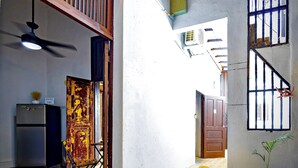 A narrow corridor with a ceiling fan, a refrigerator, a door with peeling paint, and a potted plant. - San Juan Home DownTown Perfect for family and group (San Juan)