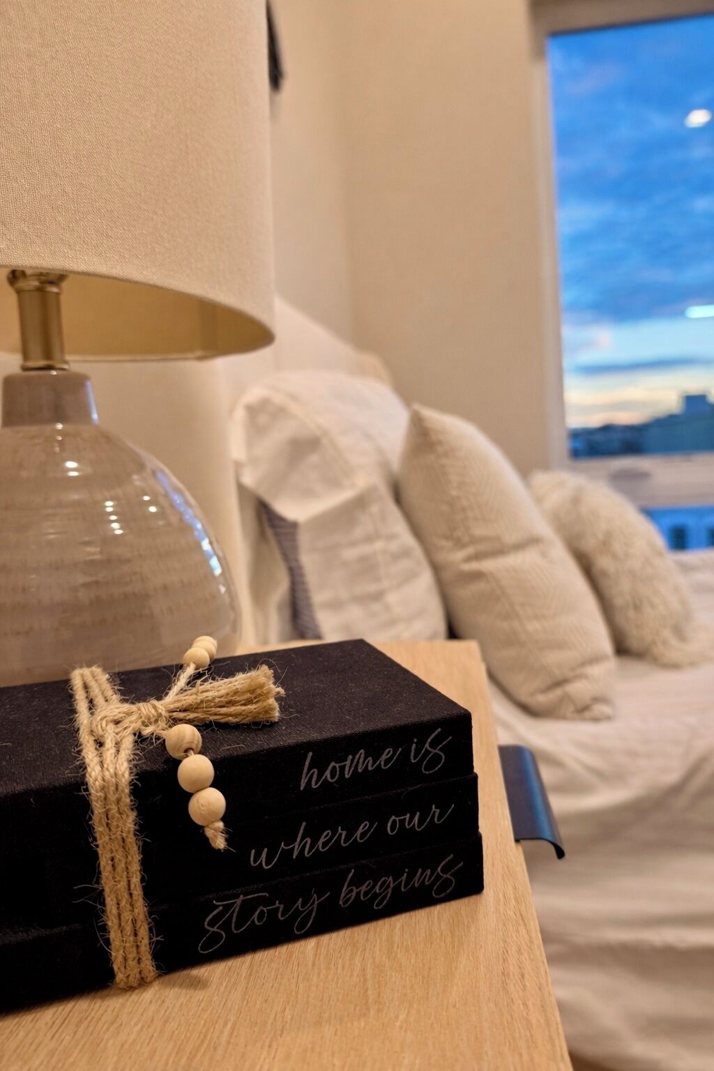 Una camera da letto accogliente con un letto, cuscini, una lampada e una scatola decorativa con un messaggio.
