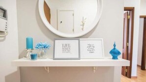 A white shelf with framed inspirational quotes, a blue candle, and a decorative blue vase. - Fantastic apartment with lots of light, in a quiet area, 200m from the metro. (Lisboa)