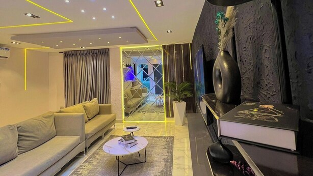 A modern living room with a sofa, coffee table, and a flat-screen TV. - AVERROES ARENA (Abuja)