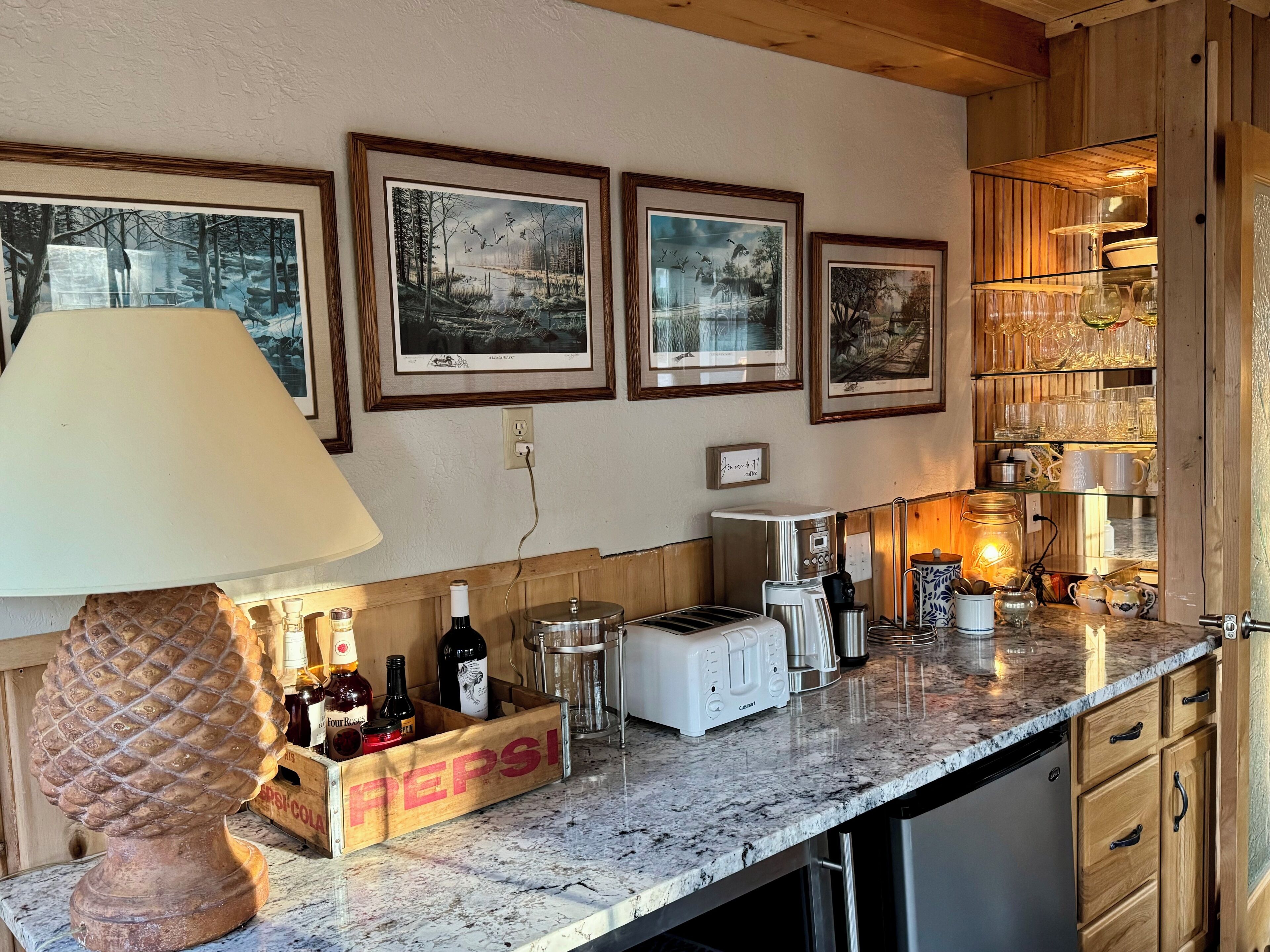 A kitchen with wooden cabinets, a marble countertop, a coffee maker, a toaster, and a wooden crate labeled "PEPSI".