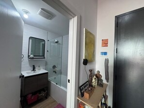 A compact bathroom with a white sink, mirror, and glass shower enclosure.