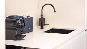 A kitchen with a coffee machine, a sink, and a faucet. - Miguel Bombarda House - 301 by LovelyStay (Porto)