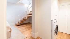 A modern apartment with a wooden staircase, a washing machine, and a minimalist design. - Miguel Bombarda House - 101 by LovelyStay (Porto)