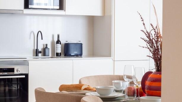 A modern kitchen with white cabinetry, a Bosch oven, a wine bottle, and a blue speaker. - Miguel Bombarda House - 402 by LovelyStay (Porto)