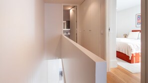 Ein modernes Hotelzimmer mit Holzboden, einem Bett mit weißer Bettwäsche und einer roten Akzentwand.