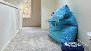 A room with a skylight, a blue bean bag, and a patterned ottoman.