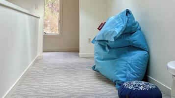 A room with a skylight, a blue bean bag, and a patterned ottoman.