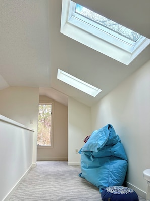 Een kamer met dakraam, een blauwe kruikzak en een gestreept voetenbankje.