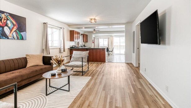 A spacious living area with a sofa, coffee table, and a dining area with a kitchen in the background. - Charming 2 Bed, 1 Bath Escape | Free Parking, WiFi (Greater Sudbury)