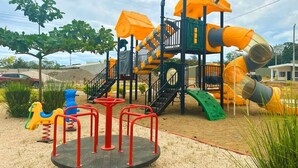 Une aire de jeux avec un toboggan, des structures d’escalade et un manège.