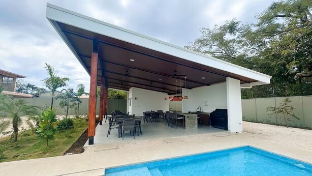 Un espace extérieur abrité comprenant une piscine, des sièges et un barbecue.