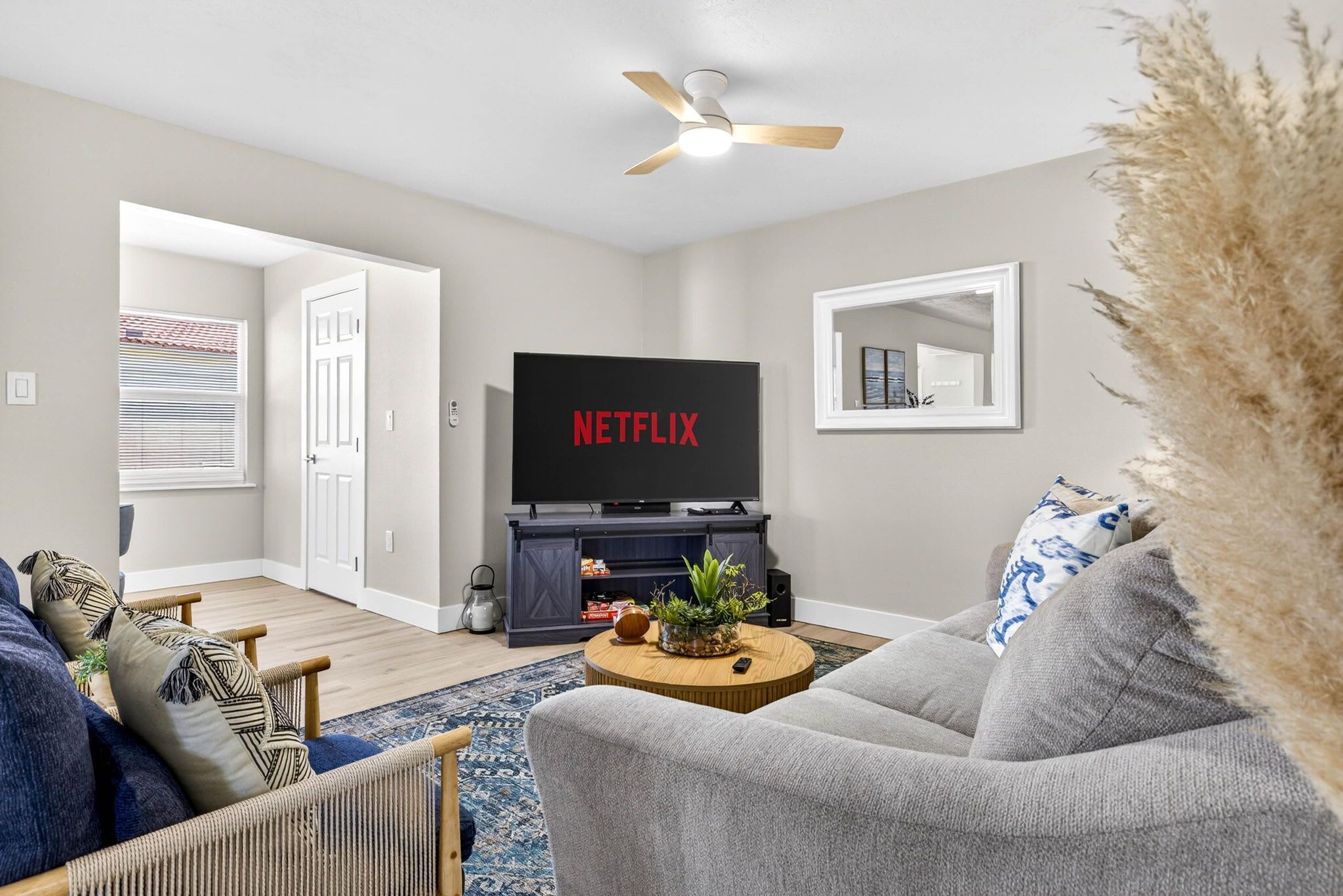 Ein Wohnzimmer mit Flachbildfernseher, Deckenventilator und einem großen Spiegel an der Wand.