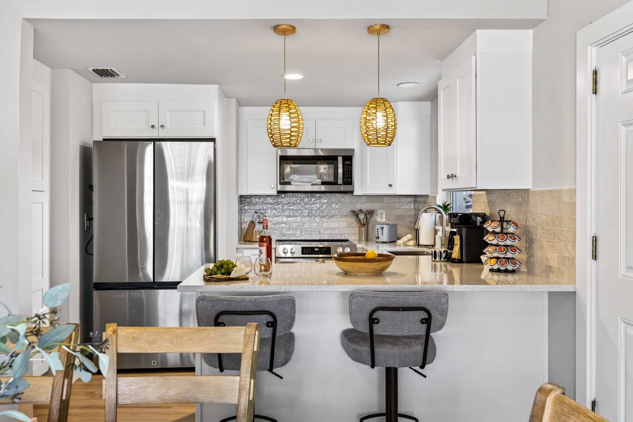A modern kitchen with white cabinets, stainless steel appliances, and a central island with bar stools.
