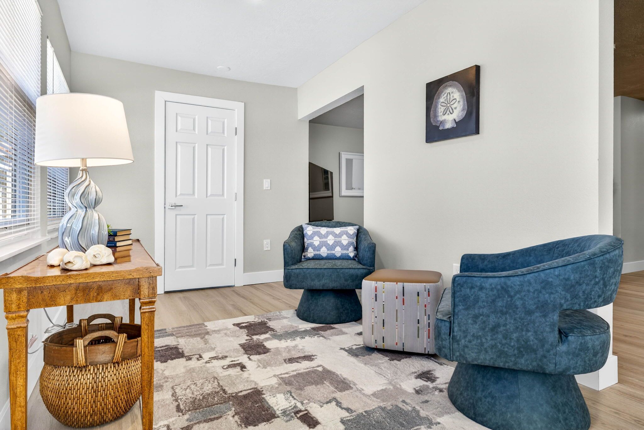 A modern living room with a wooden table, a blue armchair, and a patterned rug.