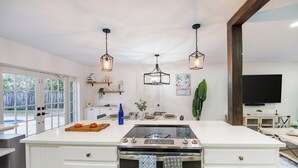 Un'ampia cucina con una grande isola, illuminazione a sospensione e vista sull'esterno.