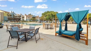 An outdoor pool area with lounge chairs, a table, and a canopy bed. - Relaxing King Suite Getaway | Sleeps 4 | Pool, Pkg (Austin)