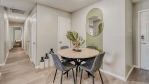 A dining area with a round table, four chairs, and a vase of flowers. - Urban Chic Getaway 2B | Sleeps 6 | Pool, Prkg, W/D (Austin)