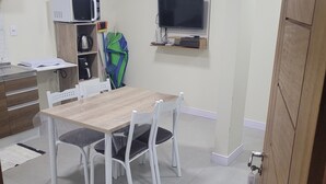 A compact kitchen with a microwave, kettle, and a small TV on a shelf. - Furnished one-bedroom apartment in Balneário Gaivota, right in the center. (Balneário Gaivota)