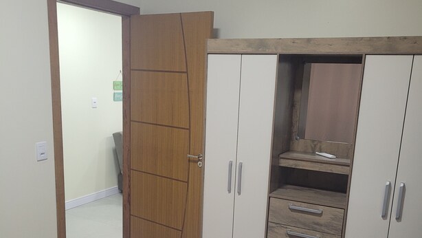 A bedroom with a bed, a wardrobe, and a desk. - Furnished one-bedroom apartment in Balneário Gaivota, right in the center. (Balneário Gaivota)