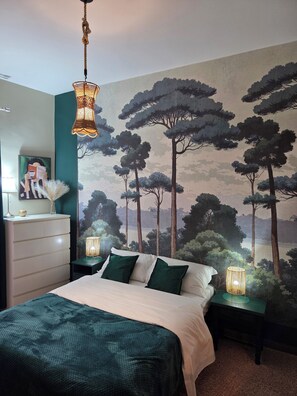 A bedroom with a bed, nightstands, a dresser, a painting, and a mural of trees. - Home in Rome - Caracalla boutique (Roma)