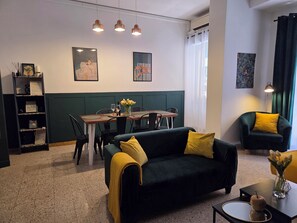 A modern living room with a green sofa, a dining table, and a bookshelf. - Home in Rome - Caracalla boutique (Roma)